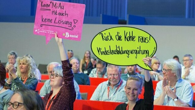 zwei Personen halten Schilder mit Slogans zur Erhöhung der Mindestausbildungsvergütung