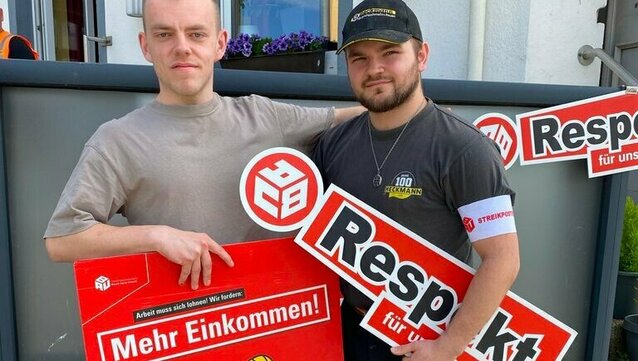 zwei Personen halten Schilder auf einem Streik